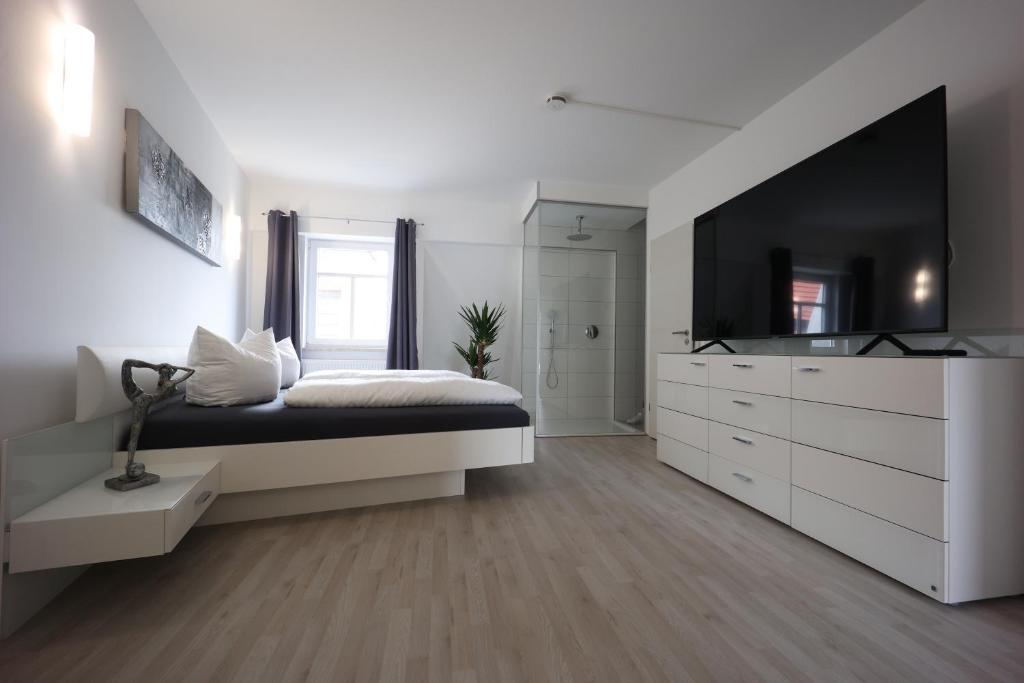 a white bedroom with a large bed and a television at Eat and Stay in Bad Salzungen