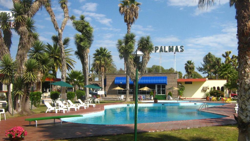 una piscina en un complejo con palmeras en Hotel Las Palmas Midway Inn, en Matehuala