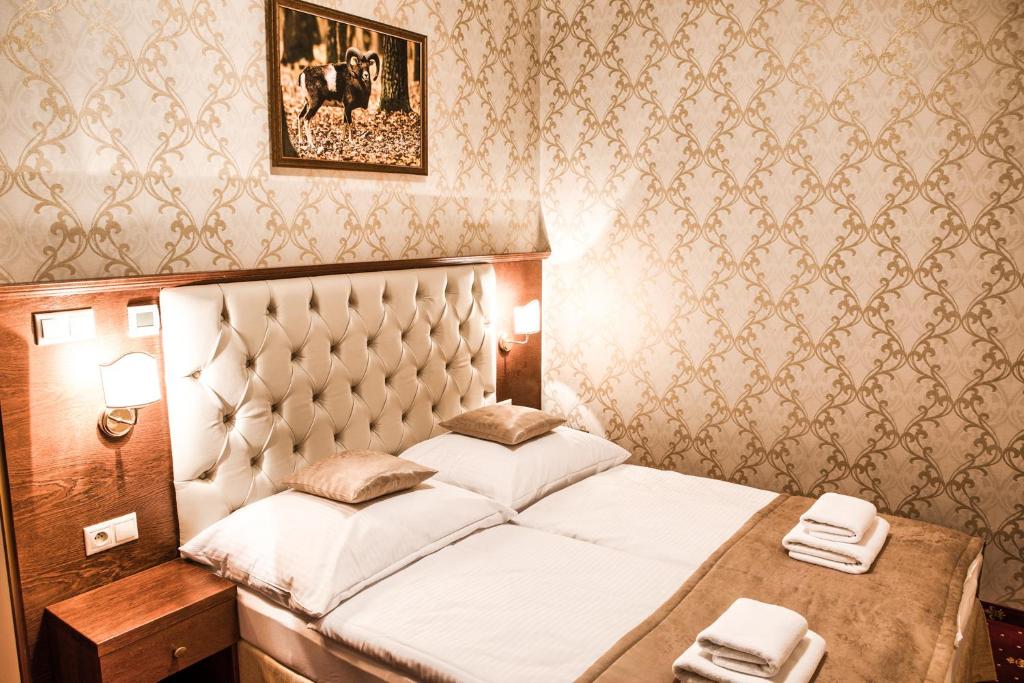 ein Schlafzimmer mit einem Bett in einem Zimmer mit Tapete in der Unterkunft Chateau Hunting *** in Hontianske Nemce