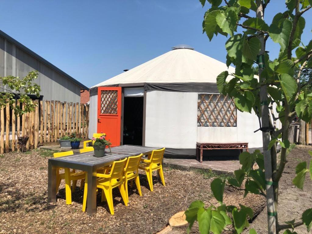 a table with yellow chairs and a tent at Authentieke Yurt voor 6 personen in Reutum