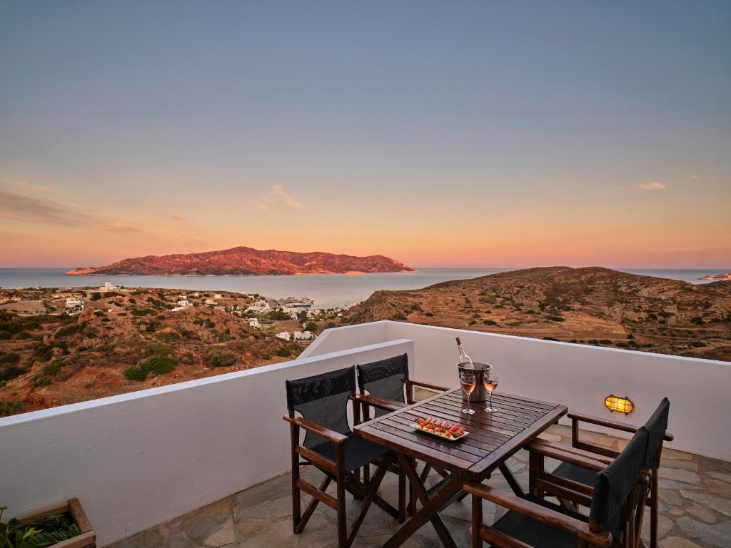 una mesa y sillas en un balcón con vistas al océano en Aria Kimolos Residence, en Kimolos