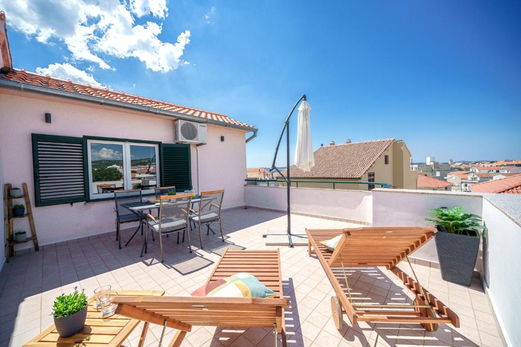 a balcony with wooden furniture and a table and chairs at Family Petrov Apartments in Vodice