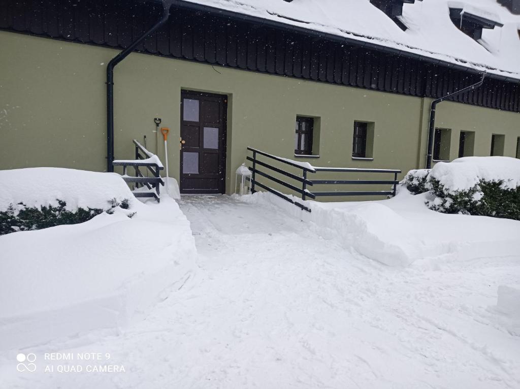 a snow covered yard next to a building at apartmány Kynast in Albrechtice v Jizerských horách