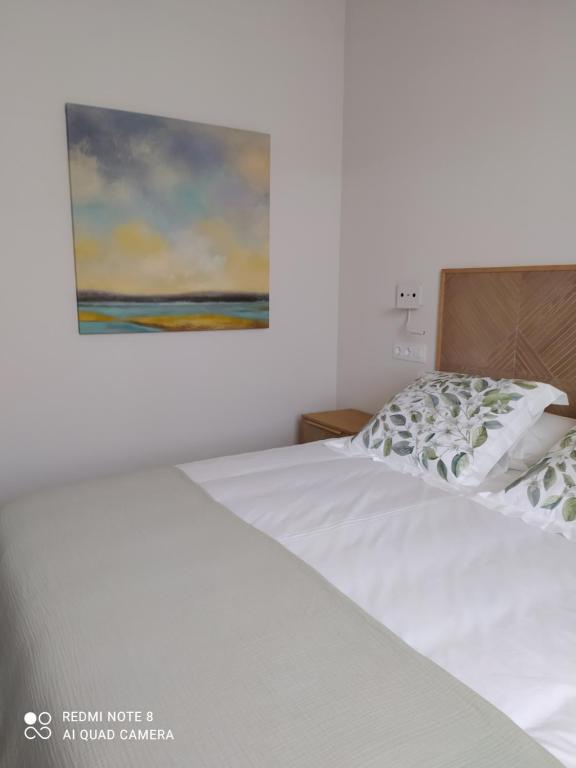 sypialnia z białym łóżkiem i obrazem na ścianie w obiekcie Apartamentos Pontedeume Riadoeume w mieście Puentedeume