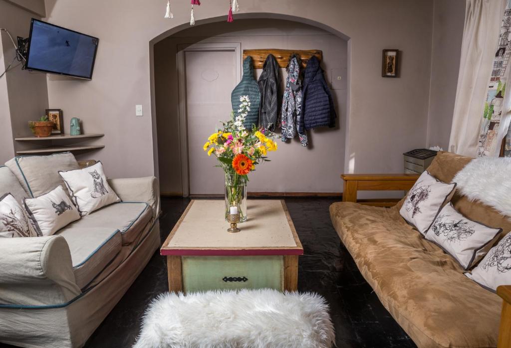 een woonkamer met een bank en een tafel met bloemen bij La Justina Hostel in Bariloche