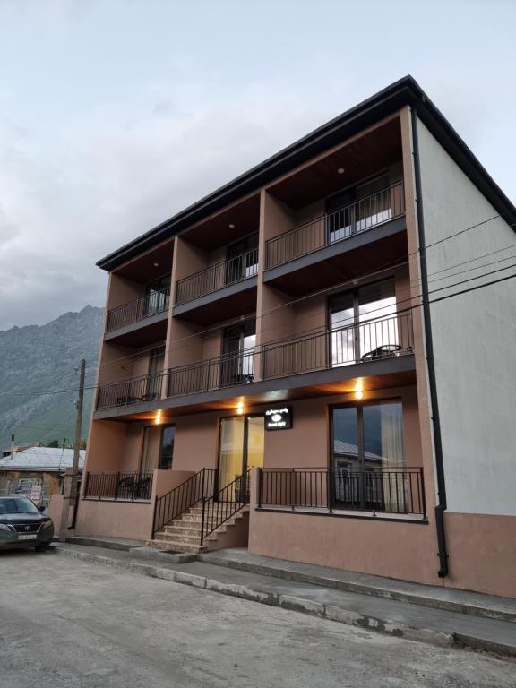an apartment building with balconies and a parking lot at Hotel Sweet Night in Kazbegi