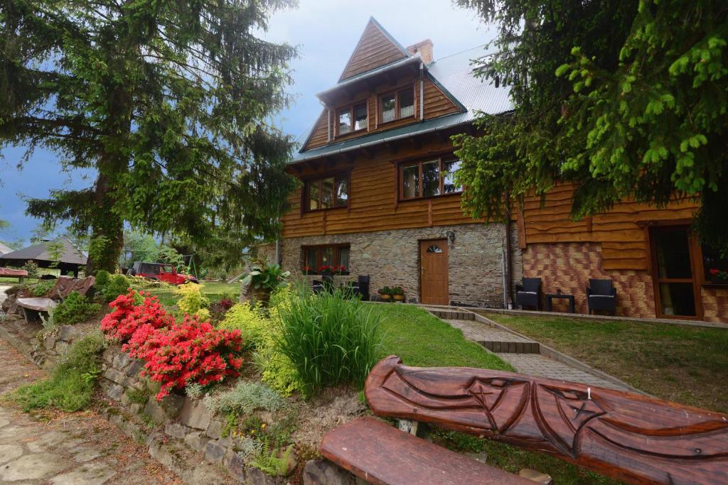 a wooden house with a bench in front of it at Pensjonat Lesniczówka in Polańczyk