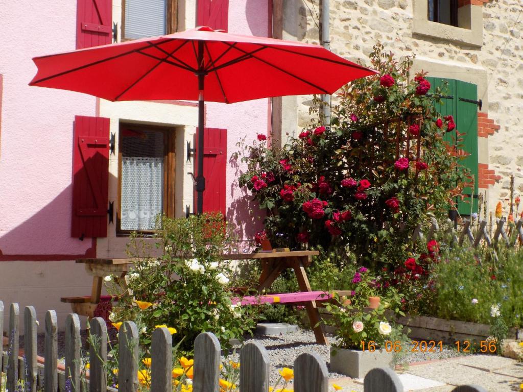 un parapluie rouge assis devant une maison dans l'établissement Aux Roses, à Vrolle