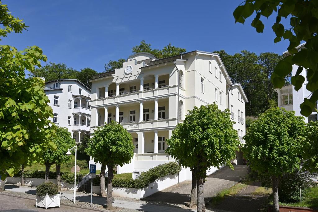 un edificio blanco con árboles delante de él en Villa Celia, en Ostseebad Sellin