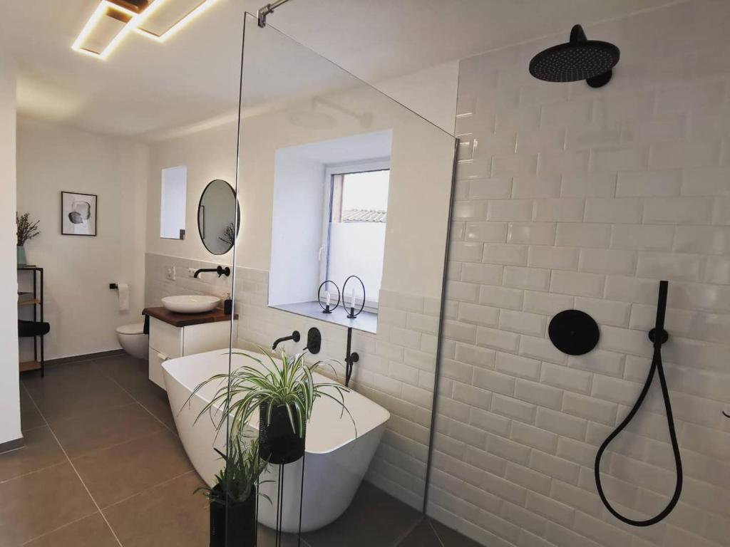 PettingにあるModerne Ferienwohnungen mit Designbadの浴槽とガラスのシャワー付きのバスルーム