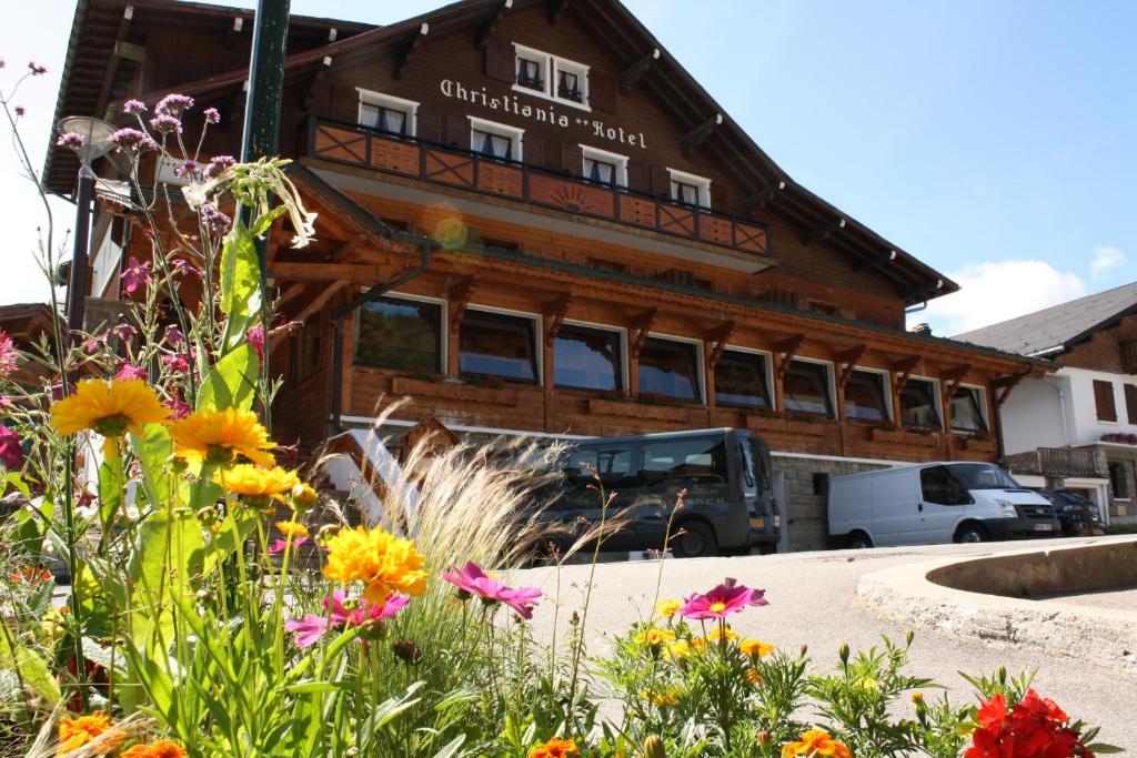 a wooden building with flowers in front of it at Hotel Le Christiania in Les Gets
