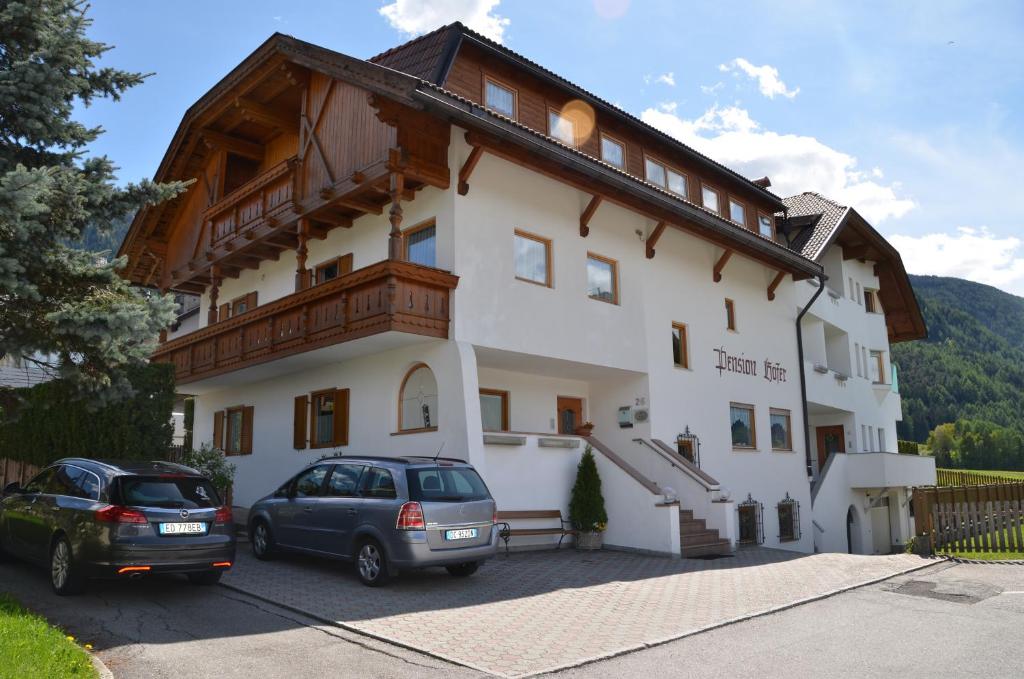 een gebouw met twee auto's ervoor geparkeerd bij Pension Hofer in Brunico