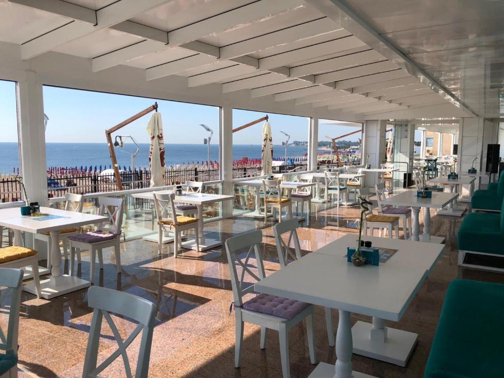 a restaurant with tables and chairs with the ocean in the background at PASHA HOTEL in Eforie Nord