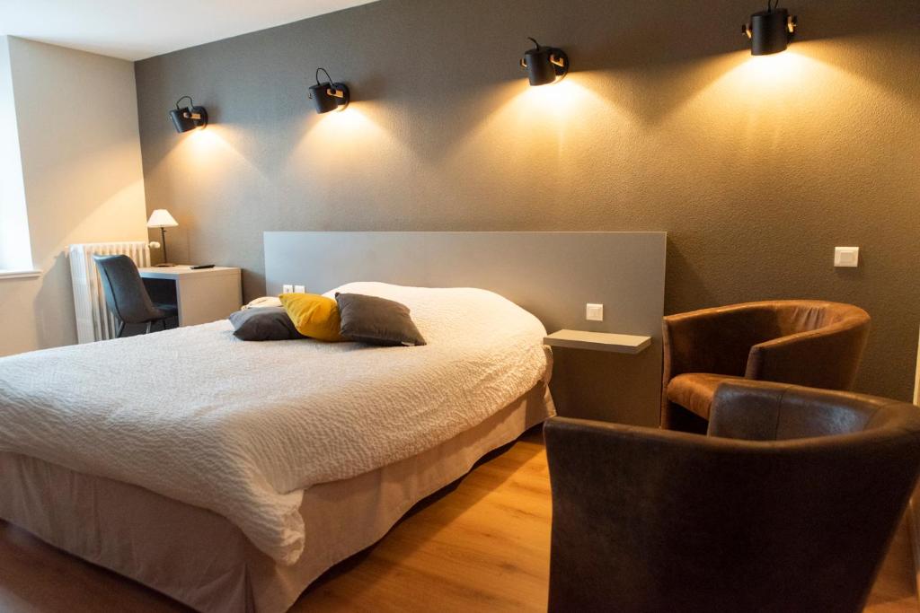 a bedroom with a bed and two chairs at Logis Hôtel Restaurant Barrey in Orchamps-Vennes