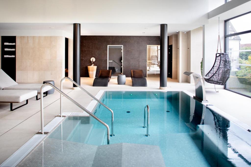 a swimming pool in a house with a living room at Le Richebourg Hôtel, Restaurant & Spa in Vosne-Romanée