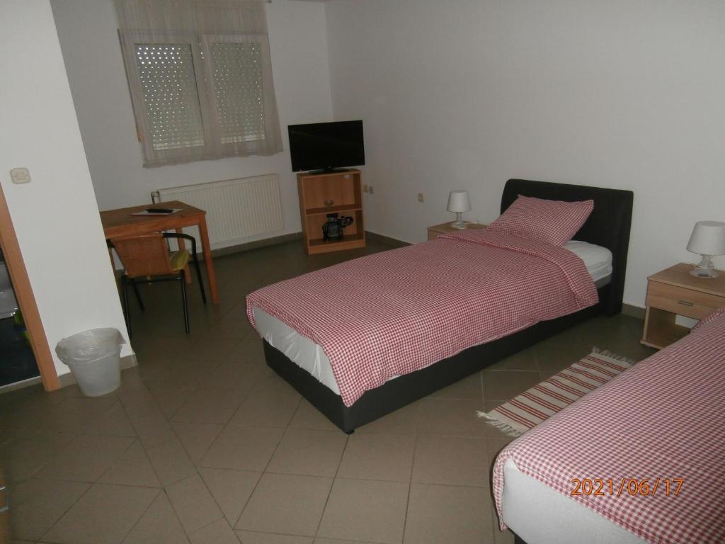 a bedroom with two beds and a table and a television at Guest House Talas in Osijek
