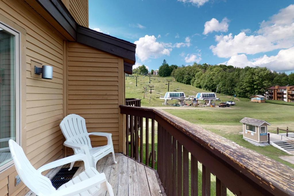 2 weiße Stühle auf einer Veranda mit Blick auf ein Feld in der Unterkunft Okemo Mountain Condo in Ludlow