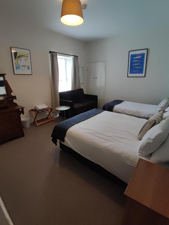 a bedroom with two beds and a couch and a chair at Rolling Wave Guesthouse in Bundoran