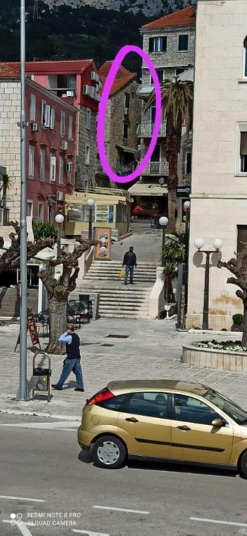a yellow car driving down a street with a pink circle at Downtown Dream Makarska in Makarska