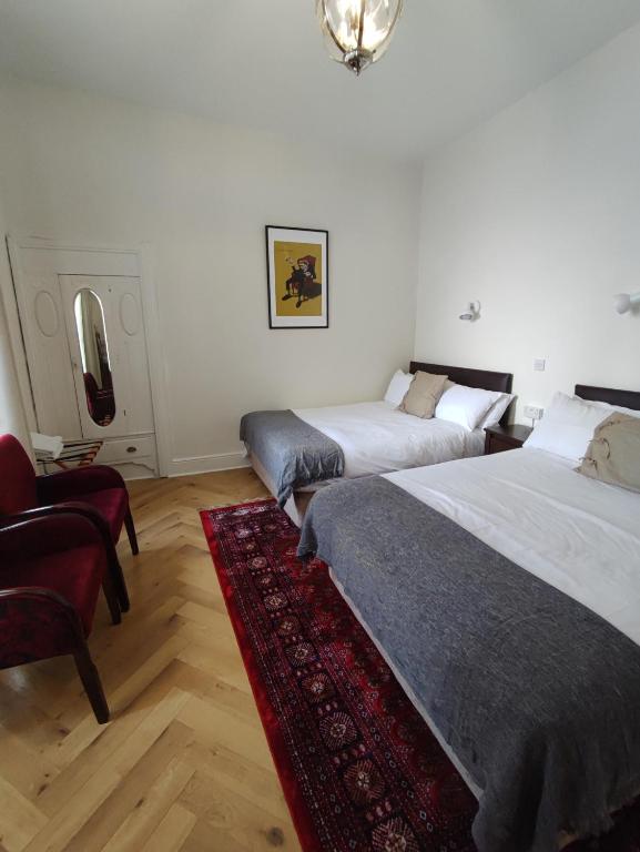 a bedroom with two beds and a red rug at Rolling Wave Guesthouse in Bundoran