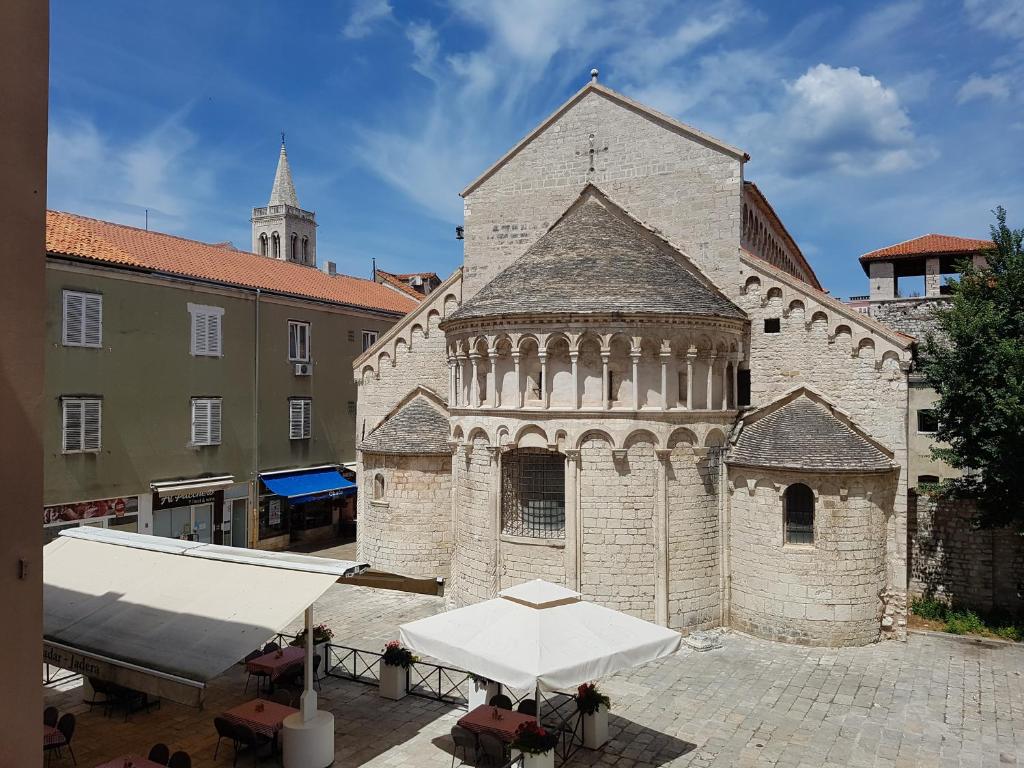 an old building with a white umbrella in front of it at Modern room old Town - Zadar in Zadar