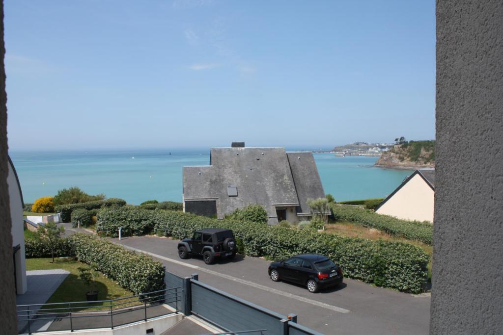 twee auto's rijden over een weg voor een gebouw bij Maison vue mer Granville in Granville