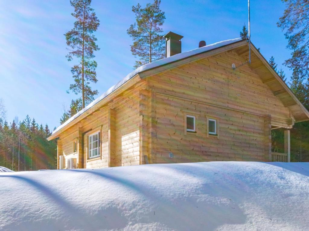 a wooden house with snow in front of it at Holiday Home Kaitaranta by Interhome in Kyyrö