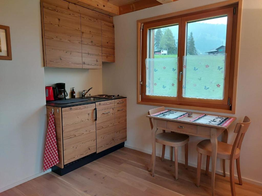 eine Küche mit einem Tisch, einem Waschbecken und einem Fenster in der Unterkunft Apartment Lärchehuus by Interhome in Adelboden