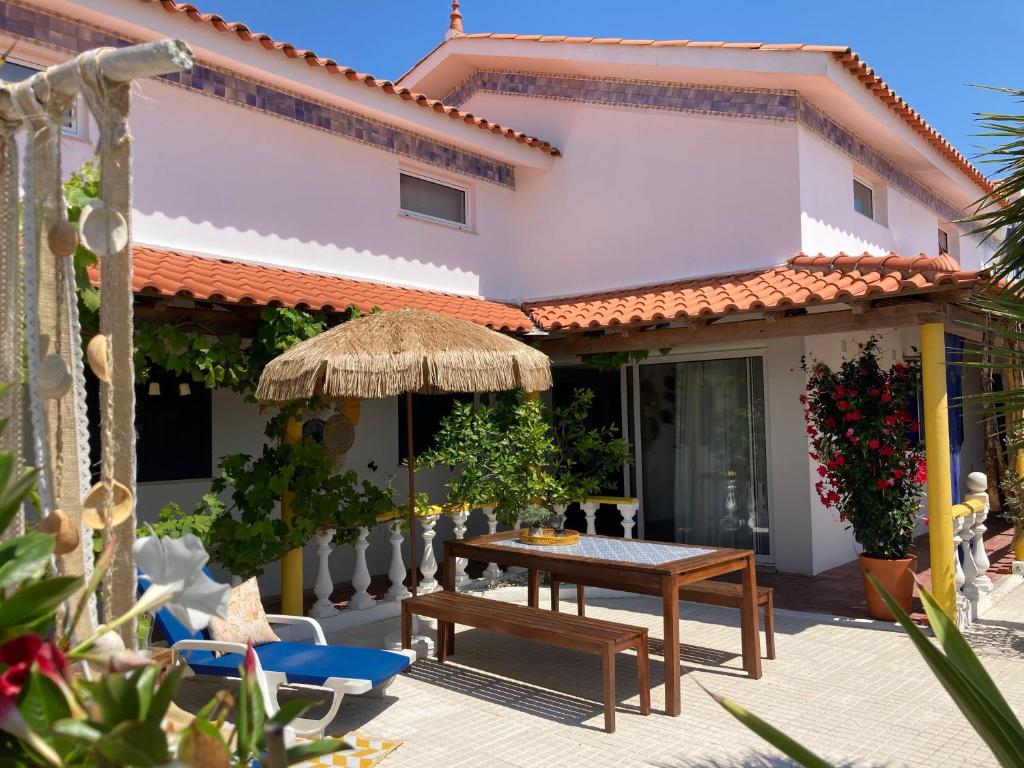 eine Terrasse mit einem Tisch und Stühlen sowie ein Haus in der Unterkunft Bico das flores in Praia de Mira