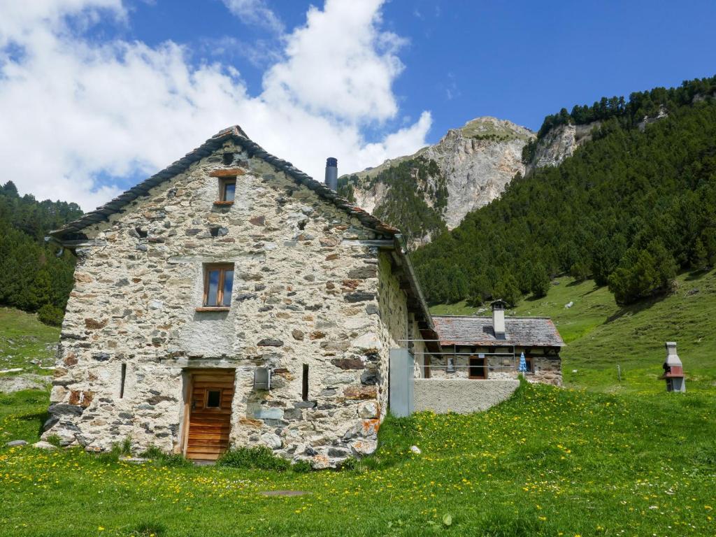 una vecchia casa in pietra in un campo con una montagna di Holiday Home Rustico Dolomia by Interhome ad Acquacalda