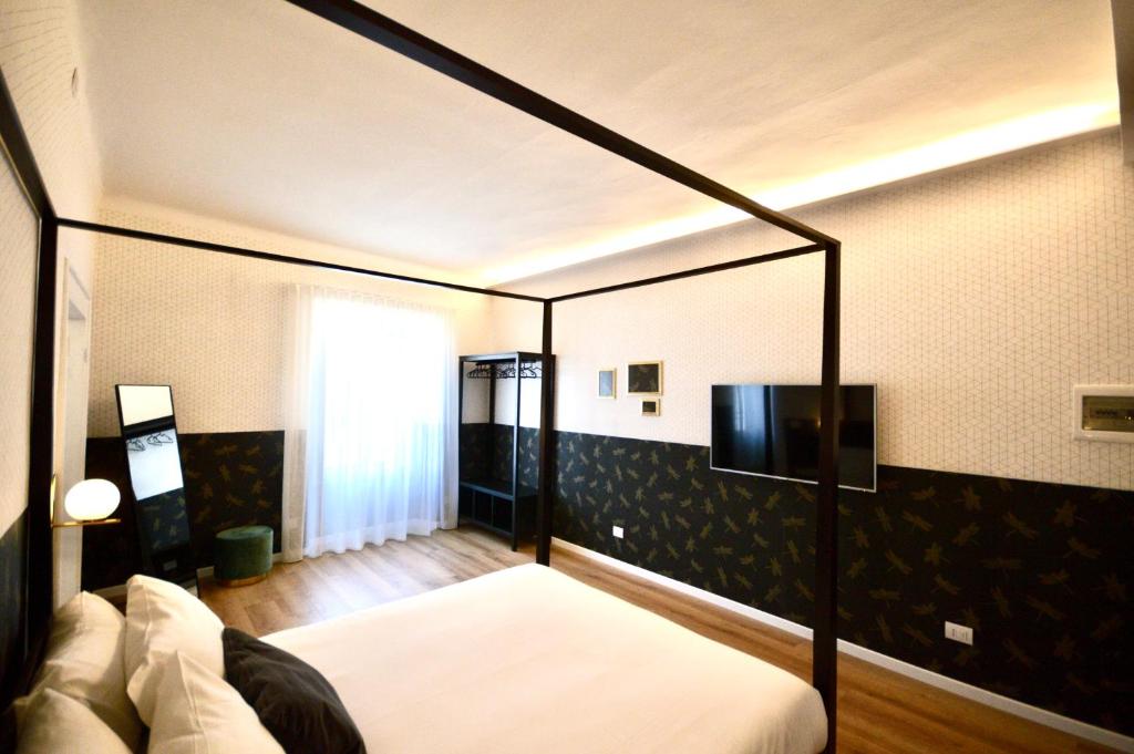 sypialnia z łóżkiem z baldachimem i telewizorem z płaskim ekranem w obiekcie Room Verona Ai Conti w Weronie