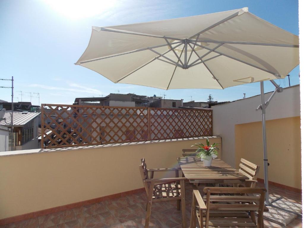 eine Terrasse mit einem Tisch und einem Sonnenschirm auf dem Dach in der Unterkunft Residence Ideal in Alcamo