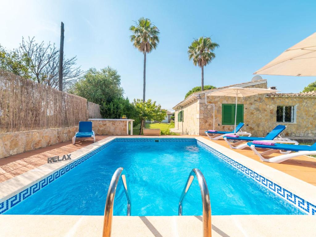 a swimming pool with two chairs and a house at Villa Can Delfin by Interhome in Alcudia