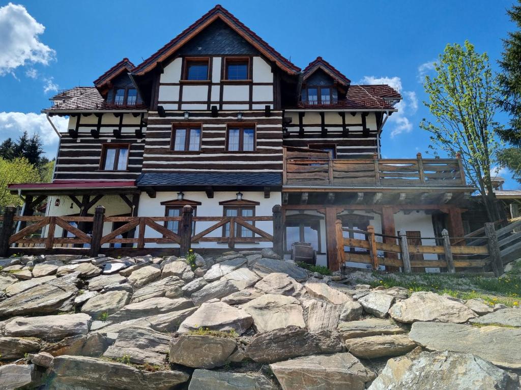 a large wooden house on top of a stone wall at Apartamenty Jagusia in Duszniki Zdrój