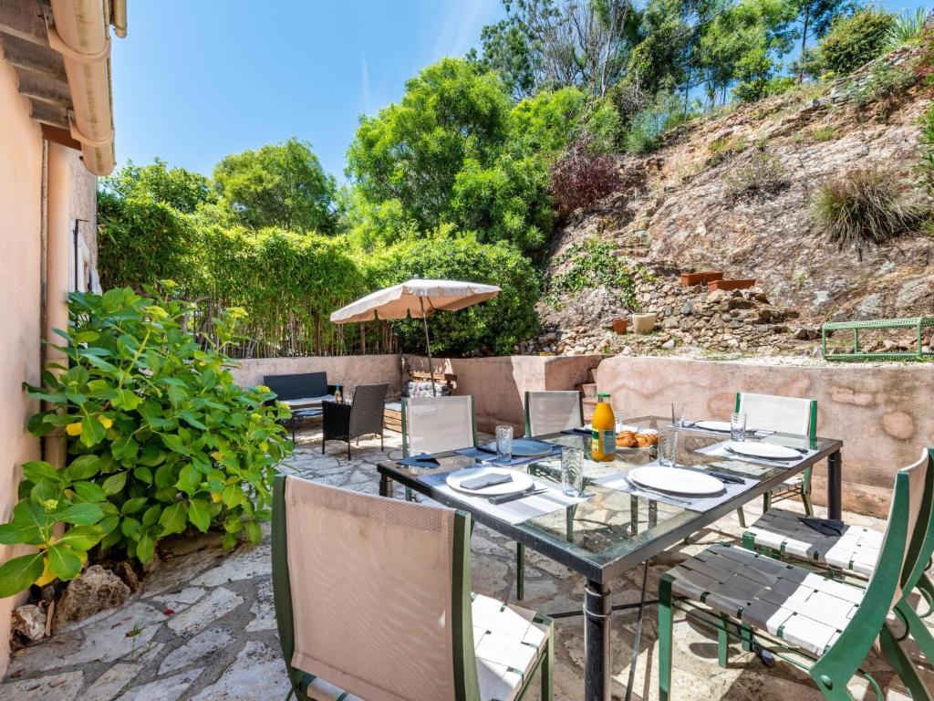 een tafel met stoelen en een parasol op een patio bij Apartment Les Chênes by Interhome in Gassin