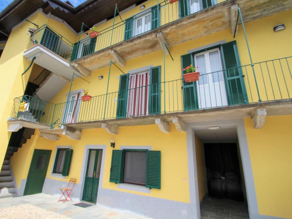 - un bâtiment jaune avec des portes et des balcons verts dans l'établissement Apartment Giardino del Bosso-1 by Interhome, à Germignaga
