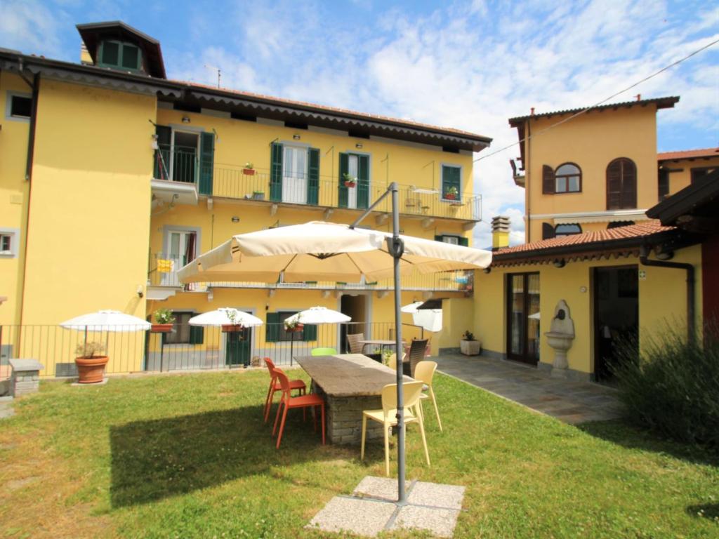 eine Terrasse mit einem Tisch, Stühlen und Sonnenschirmen in der Unterkunft Apartment Giardino del Bosso-2 by Interhome in Germignaga