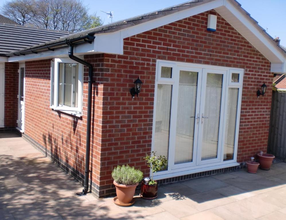 a red brick house with a white door at Quiet, cosy annexe room in Rough Close