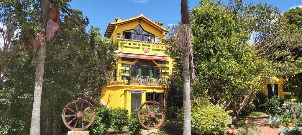 ein gelbes Haus mit zwei Wagenrädern davor in der Unterkunft Casa Realidad y Ensueño in Villa de Leyva