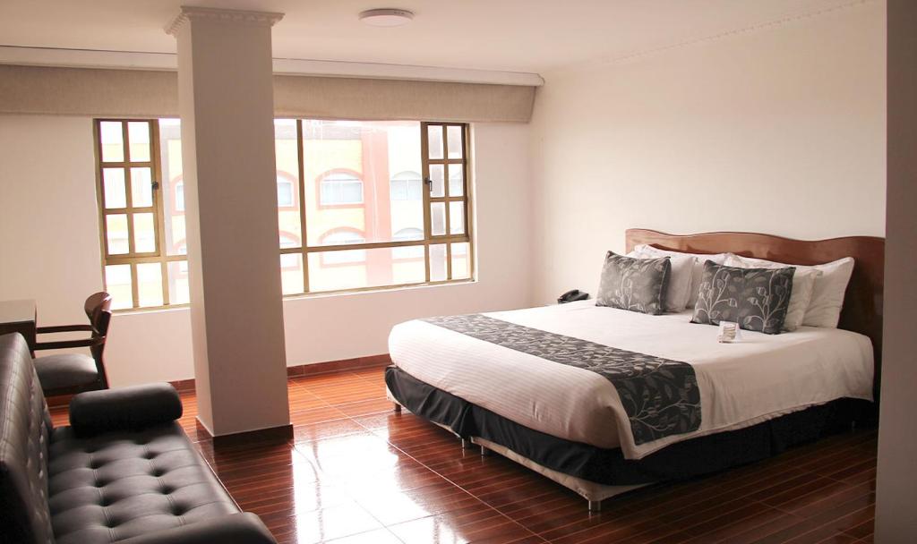 a bedroom with a bed and a couch and windows at Hotel Salitre Real in Bogotá