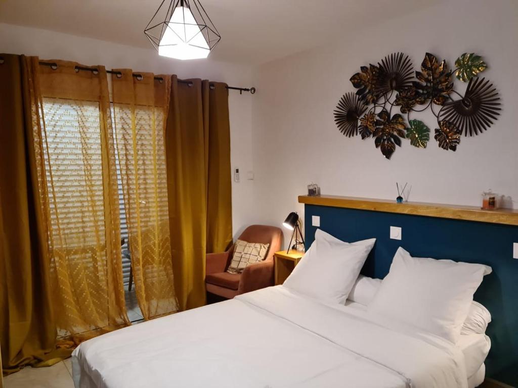 1 dormitorio con 1 cama blanca y 1 silla en Yangou Appart 1, en Mamoudzou