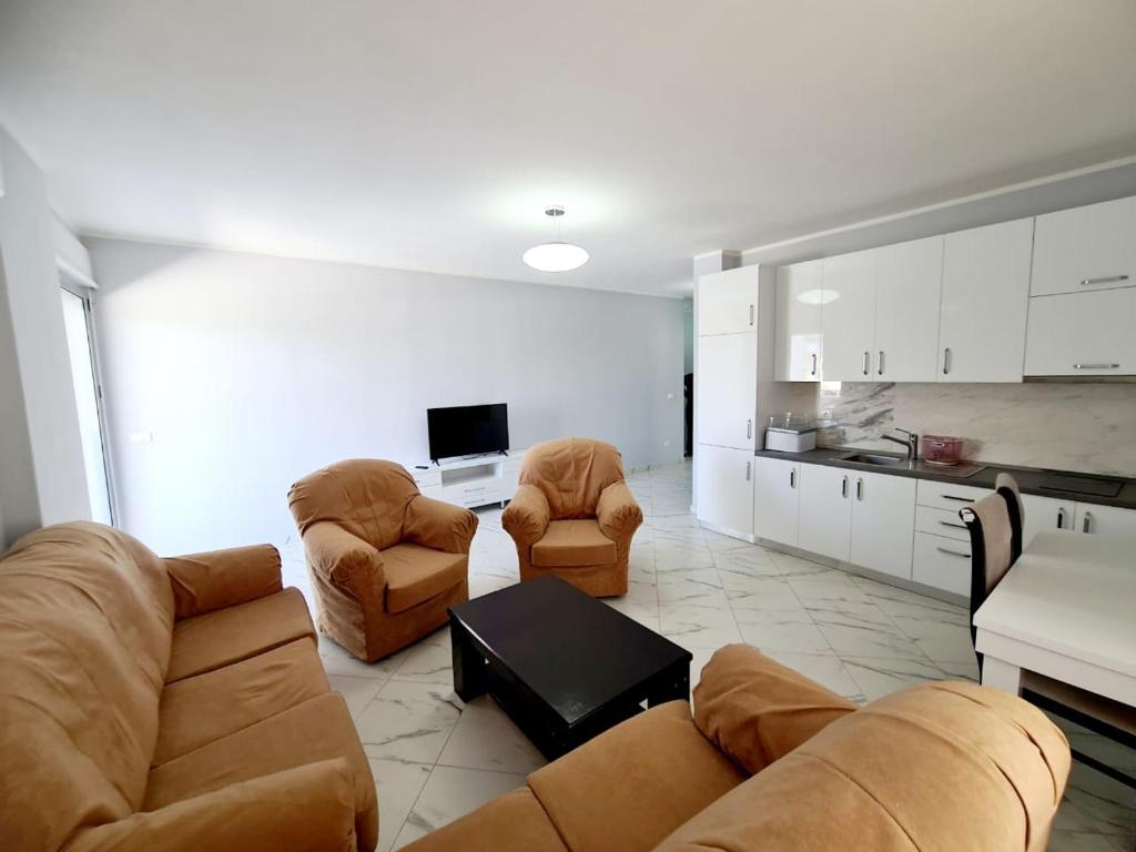 a living room with a couch and chairs and a kitchen at Sky - Apartment - Brown in Vlorë