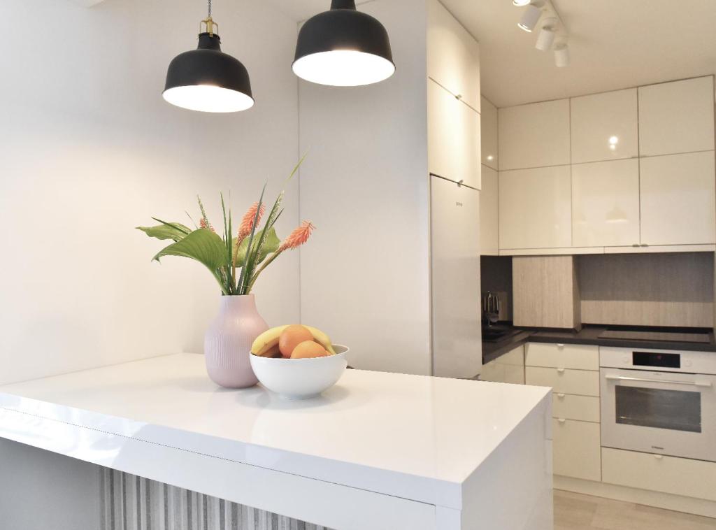 a white kitchen with a bowl of fruit on a counter at Apartment Central in Bajina Bašta