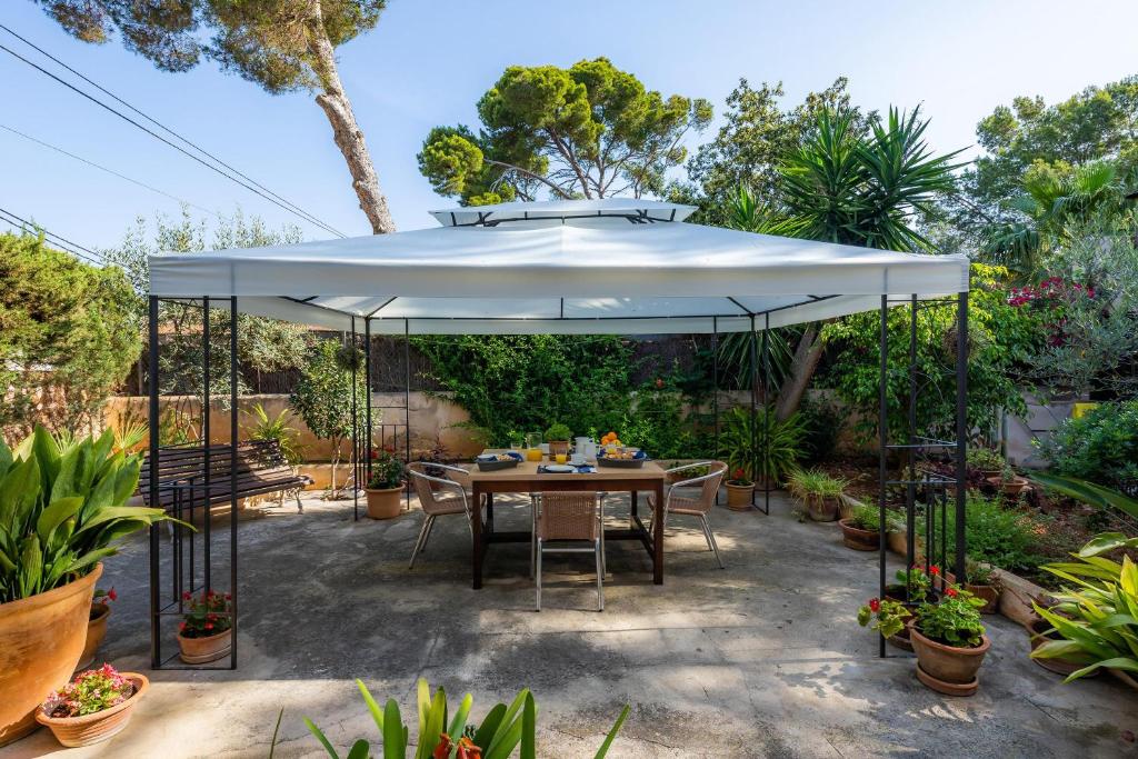 a patio with a table and a large white umbrella at Na Forana in Cala Ratjada