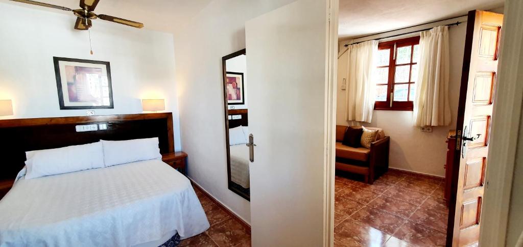 a bedroom with a white bed and a chair at Granada Apartments Familiar Deluxe in Portinatx