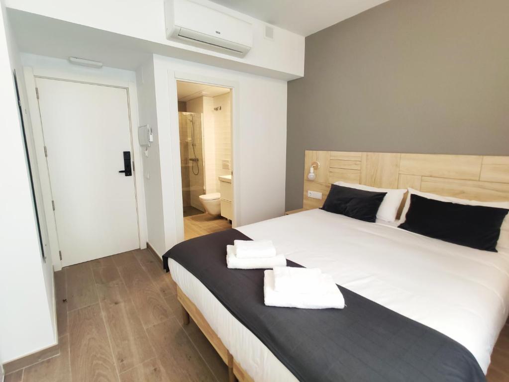 a bedroom with a large bed with two towels on it at GLOBAL Apartments & Rooms in Barcelona