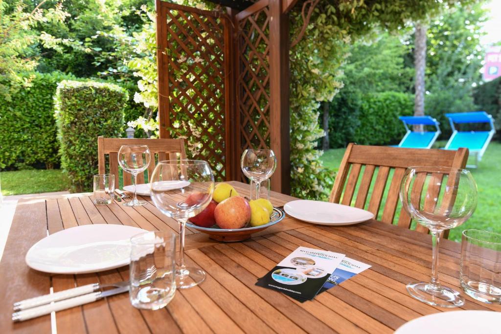 einen Holztisch mit Weingläsern und eine Schale Obst in der Unterkunft Bell'Italia Holiday Apartment Peschiera in Peschiera del Garda