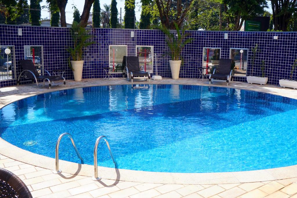 uma grande piscina azul com cadeiras à volta em Hotel Golden Park Uberaba em Uberaba