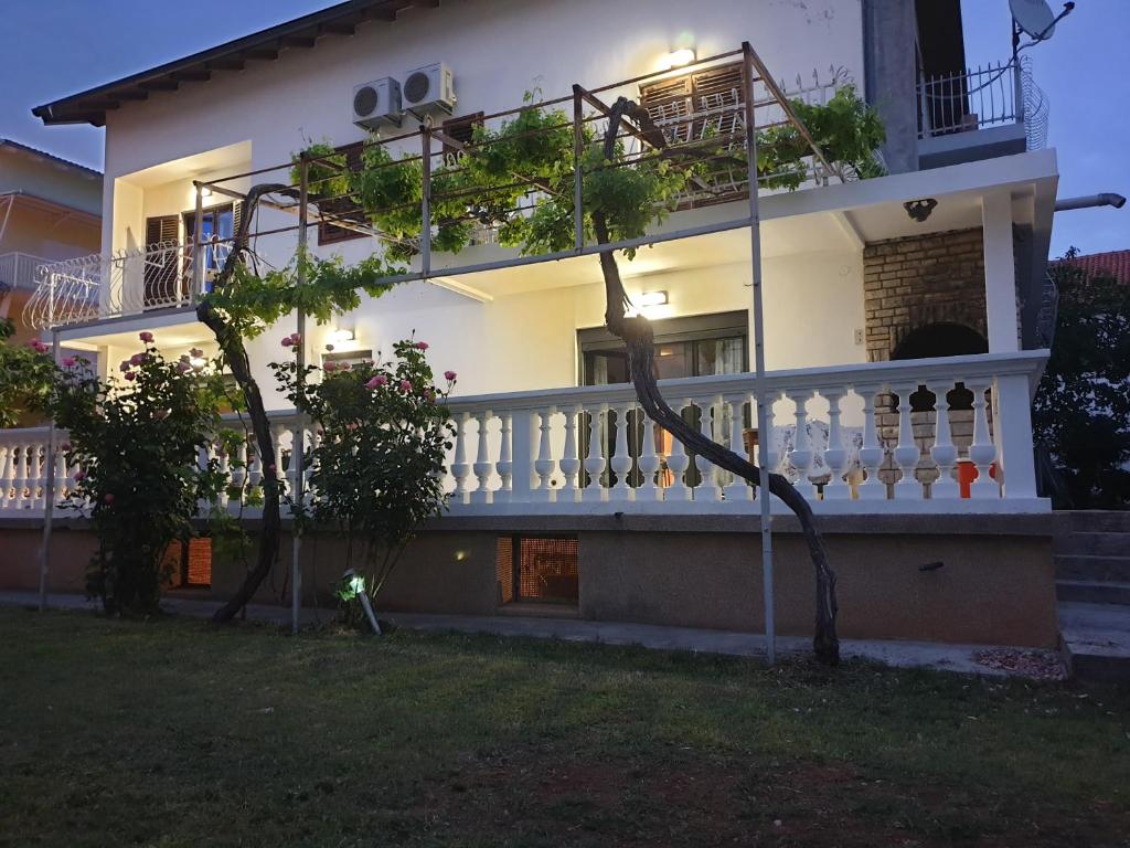una casa bianca con un balcone e un cortile di Assato Retro Apartment a Vodice