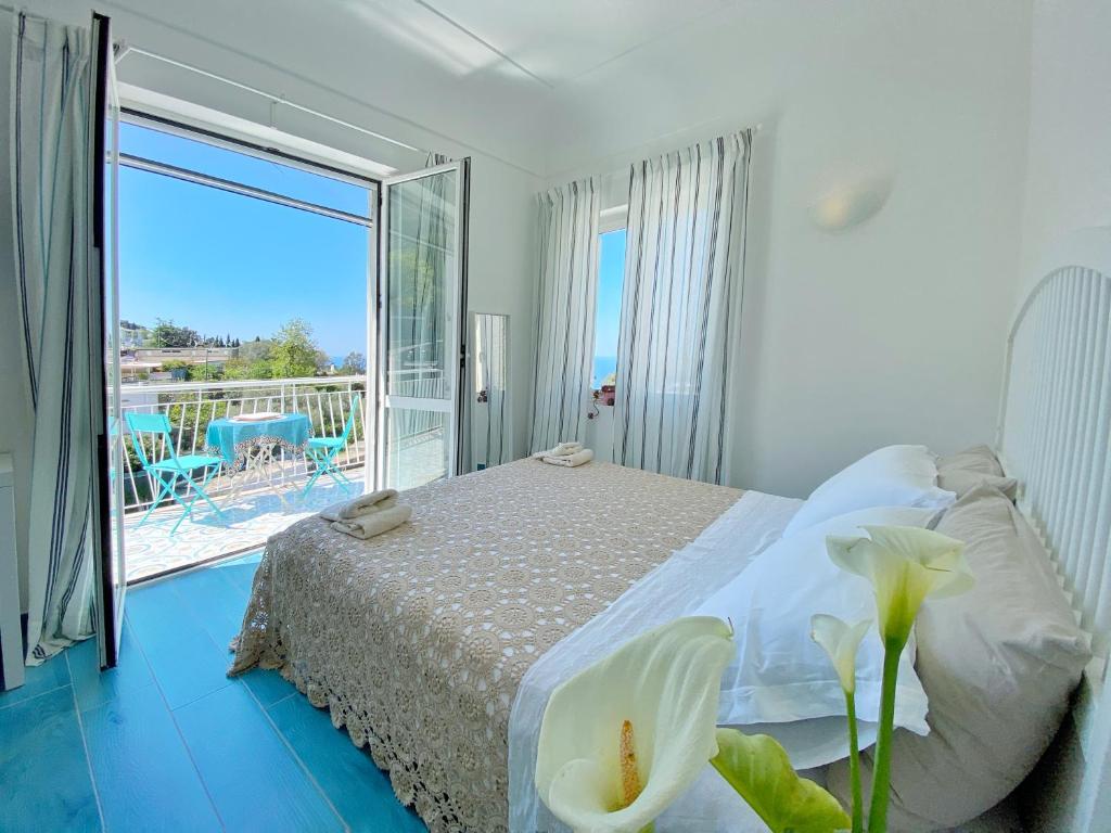 a bedroom with a bed and a balcony with a view at Casa OIKIA Anacapri in Anacapri